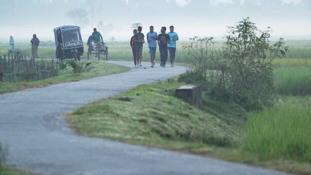 View of young men jogging on a rural road Bangladesh.