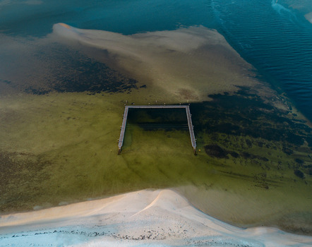 Aerial view of the Emu Point jetty extending into the shallow turquoise waters and sandy seabed of Emu Point Western Australia Australia. Aerial view of the Emu Point jetty extending into the shallow turquoise waters and sandy seabed of Emu Point Western Australia Australia.