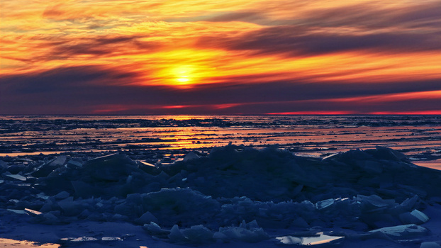 Aerial view of a frozen sea with jagged ice floes under a vibrant sunset sky in Latvia. Aerial view of a frozen sea with jagged ice floes under a vibrant sunset sky in Latvia.