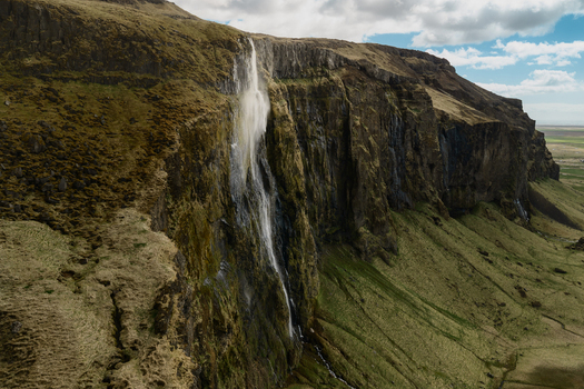 Aerial view of Seljalandsfoss waterfall cascading down a steep moss covered cliff face in Rangarthing eystra Iceland. Aerial view of Seljalandsfoss waterfall cascading down a steep moss covered cliff face in Rangarthing eystra Iceland.