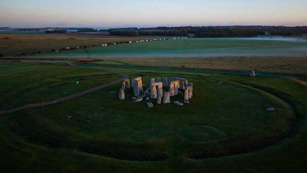 Aerial view of Stonehenge surrounded by green fields and ancient earthworks at sunrise in Salisbury England United Kingdom. Aerial view of Stonehenge surrounded by green fields and ancient earthworks at sunrise in Salisbury England United Kingdom.