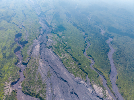Aerial view of the volcanic landscape showing the aftermath of Mount Semeru eruption with dark ash deposits cutting through lush green vegetation in Pronojiwo East Java Indonesia.