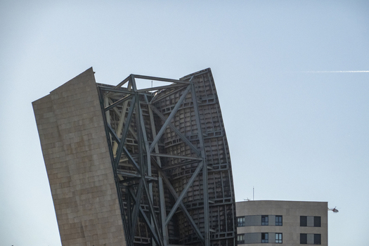 View of the modern metal framework and stone panels of the Guggenheim Museum Bilbao under a clear blue sky in Bilbao Euskadi Spain. View of the modern metal framework and stone panels of the Guggenheim Museum Bilbao under a clear blue sky in Bilbao Euskadi Spain.