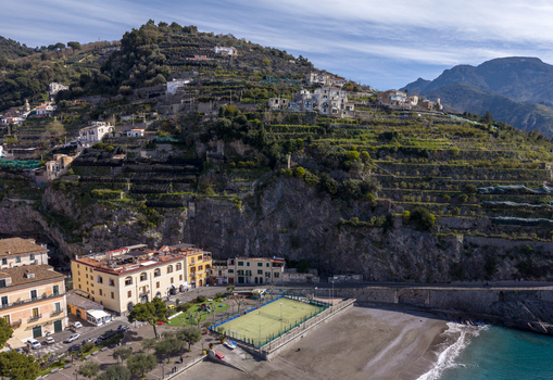 Aerial view of the sun kissed beach nestled beside the vibrant green court and buildings at the foot of terraced hills Minori Campania Italy. Aerial view of the sun kissed beach nestled beside the vibrant green court and buildings at the foot of terraced hills Minori Campania Italy.