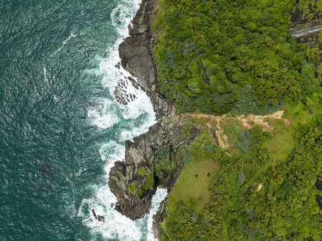 Aerial view of the rugged coastline where turquoise waters crash against dark rocks contrasting with the vibrant green vegetation Gunungkidul Regency Daerah Istimewa Yogyakarta Indonesia. Aerial view of the rugged coastline where turquoise waters crash against dark rocks contrasting with the vibrant green vegetation Gunungkidul Regency Daerah Istimewa Yogyakarta Indonesia.