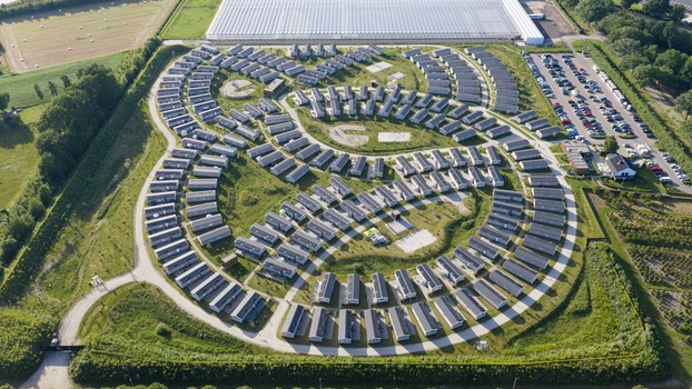 Aerial view of a modern holiday park with circular rows of cabins green lawns and a large greenhouse in the background in Venlo Limburg Netherlands. Aerial view of a modern holiday park with circular rows of cabins green lawns and a large greenhouse in the background in Venlo Limburg Netherlands.