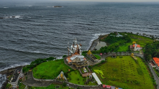 Aerial view of the iconic Murudeshwar Temple featuring the massive Shiva statue situated on a lush green headland overlooking the Arabian Sea in Murdeshwar Karnataka India.