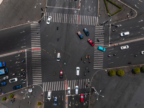Aerial view of a busy urban intersection with cars motorcycles and scooters navigating the crosswalks and lanes under bright daylight Vietnam. Aerial view of a busy urban intersection with cars motorcycles and scooters navigating the crosswalks and lanes under bright daylight Vietnam.