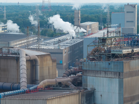 Aerial view of the Genk Zuid Rechteroever industrial complex featuring steel manufacturing facilities large pipes and industrial chimneys emitting smoke in Genk Vlaanderen Belgium. Aerial view of the Genk Zuid Rechteroever industrial complex featuring steel manufacturing facilities large pipes and industrial chimneys emitting smoke in Genk Vlaanderen Belgium.