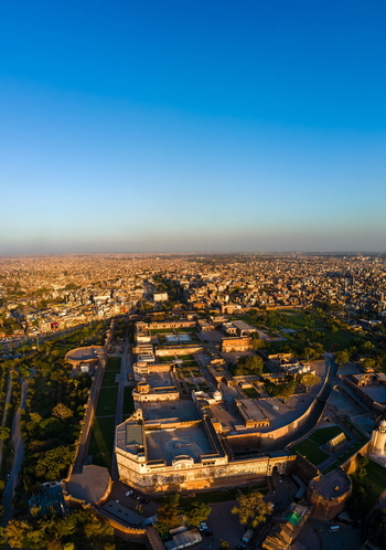 Aerial view of Lahore Fort a historic Mughal era citadel surrounded by lush gardens and the sprawling urban landscape of Lahore Punjab Pakistan.