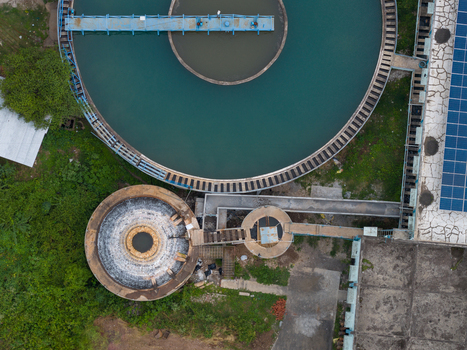 Aerial view of a water treatment facility with circular sedimentation tanks and solar panels in Karad Maharashtra India.