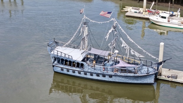 Aerial view of a striking grey pirate ship with tattered sails and an American flag docked in the murky waters Fernandina Beach Florida United States. Aerial view of a striking grey pirate ship with tattered sails and an American flag docked in the murky waters Fernandina Beach Florida United States.