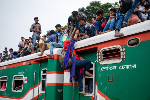 Dhaka Bangladesh 15 June 2018 View of passengers crowded on the roof of a train at Airport Railway Station with a woman climbing the side of the carriage. Dhaka Bangladesh 15 June 2018 View of passengers crowded on the roof of a train at Airport Railway Station with a woman climbing the side of the carriage.