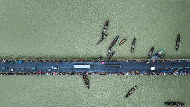 Baghabari Bangladesh 20 August 2022 Aerial view of a busy bridge crowded with people and vehicles surrounded by numerous small wooden boats navigating the river waters.