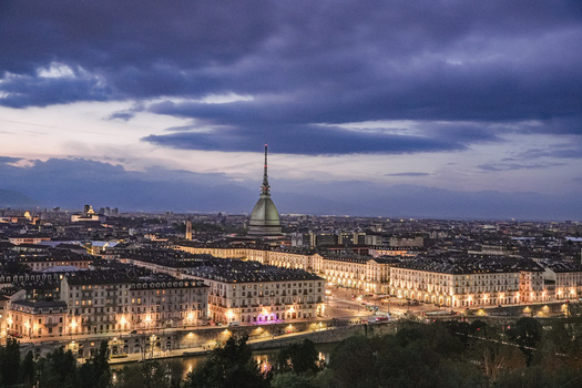 Aerial view of the Mole Antonelliana towering over the illuminated city skyline and Po river under a dramatic twilight sky in Turin Piedmont Italy. Aerial view of the Mole Antonelliana towering over the illuminated city skyline and Po river under a dramatic twilight sky in Turin Piedmont Italy.