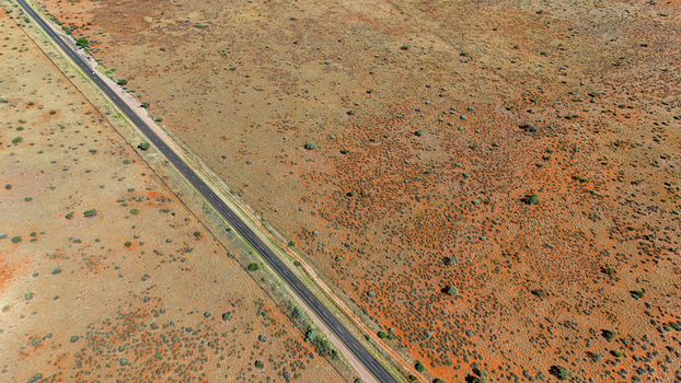 Aerial view of a stark desolate highway cutting through the arid landscape a ribbon of gray against the ochre earth Karoo Desert Northern Cape South Africa. Aerial view of a stark desolate highway cutting through the arid landscape a ribbon of gray against the ochre earth Karoo Desert Northern Cape South Africa.