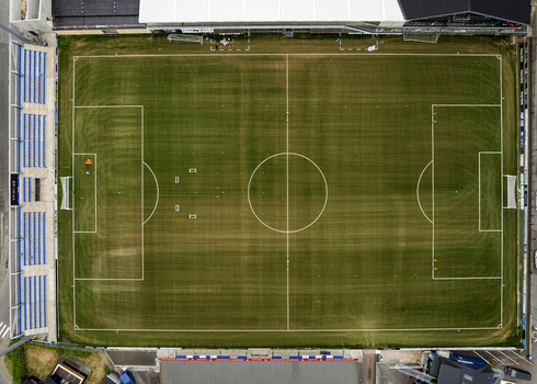 Aerial view of the green football pitch at Djupumyra Stadium with white markings and blue spectator stands in Klaksvik Northern Isles Faroe Islands.