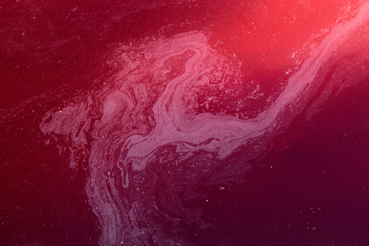 View of the deep red acidic waters of the Rio Tinto river with swirling mineral sediments and crimson textures at the Minas de Riotinto Andalusia Spain. View of the deep red acidic waters of the Rio Tinto river with swirling mineral sediments and crimson textures at the Minas de Riotinto Andalusia Spain.