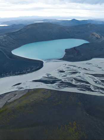 Aerial view of Skyggnisvatn volcanic lake surrounded by dark volcanic terrain and glacial river channels in Hella Rangarthing ytra Iceland. Aerial view of Skyggnisvatn volcanic lake surrounded by dark volcanic terrain and glacial river channels in Hella Rangarthing ytra Iceland.