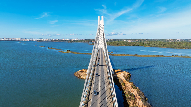 Aerial view of the Arade Bridge spanning the Arade River with cars driving across the cable stayed structure under a clear blue sky in Portimao Faro District Portugal. Aerial view of the Arade Bridge spanning the Arade River with cars driving across the cable stayed structure under a clear blue sky in Portimao Faro District Portugal.