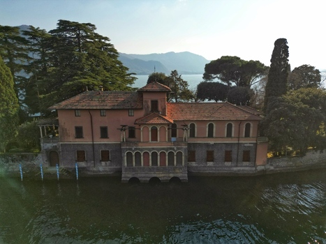 Aerial view of a historic lakeside villa with arched windows and terracotta roof tiles on the shore of Lake Iseo in Monte Isola Lombardy Italy. Aerial view of a historic lakeside villa with arched windows and terracotta roof tiles on the shore of Lake Iseo in Monte Isola Lombardy Italy.