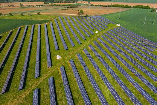 Aerial view of a solar farm with rows of photovoltaic panels on a green field surrounded by agricultural land in Kyjov South Moravian Region Czechia.