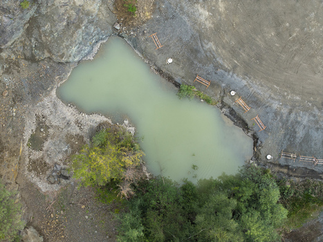Aerial view of the porphyry and diabase mine featuring a turquoise water pond rocky quarry walls surrounding trees and industrial equipment in Krakow Lesser Poland Voivode Poland. Aerial view of the porphyry and diabase mine featuring a turquoise water pond rocky quarry walls surrounding trees and industrial equipment in Krakow Lesser Poland Voivode Poland.