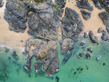 Aerial view of the rugged rocks and golden sand at Godrevy Beach with turquoise water washing against the shore in Gwithian England United Kingdom. Aerial view of the rugged rocks and golden sand at Godrevy Beach with turquoise water washing against the shore in Gwithian England United Kingdom.