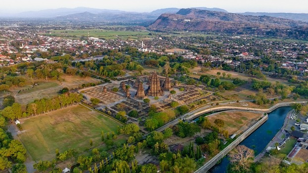 Aerial view of Prambanan Temple complex surrounded by lush green trees and historic ruins in the rural landscape of Kecamatan Prambanan Daerah Istimewa Yogya Indonesia.