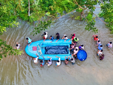 Banshkhali Upazila Chittagong Division Bangladesh 10 July 2026 Aerial view of people wading through floodwaters and pushing a blue boat carrying a covered object. Banshkhali Upazila Chittagong Division Bangladesh 10 July 2026 Aerial view of people wading through floodwaters and pushing a blue boat carrying a covered object.