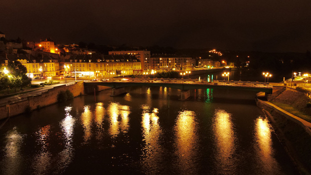 Aerial view of the bridge over the Oise River in Pontoise at night with illuminated buildings reflecting on the water and streetlights along the riverbank in Pontoise Ile de France France. Aerial view of the bridge over the Oise River in Pontoise at night with illuminated buildings reflecting on the water and streetlights along the riverbank in Pontoise Ile de France France.