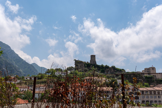 View of Kruje Castle with its historic clock tower perched on a rocky hill under a bright blue sky with white clouds in Kruje Durres County Albania.