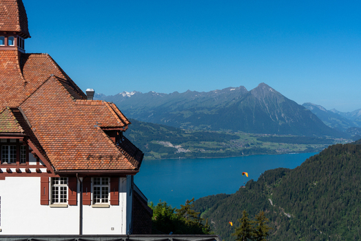 View of the Harder Kulm restaurant with its red tiled roof overlooking the turquoise waters of Lake Brienz and the Bernese Alps in Unterseen Canton of Bern Switzerland.