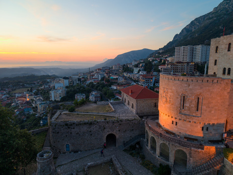 Aerial view of Kruje Castle with its historic stone walls and round tower overlooking the town and mountains during a golden sunset Kruje Durres County Albania.