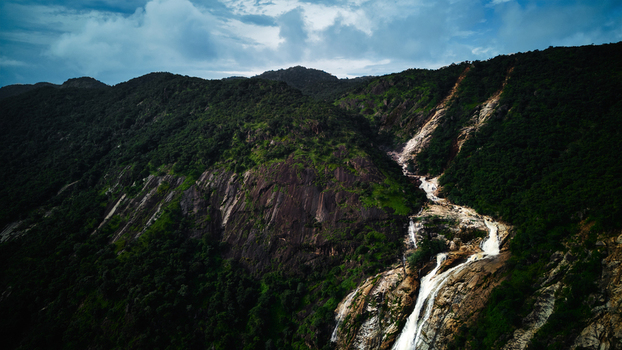 Aerial view of a cascade of water tumbling down a rocky slope amidst lush green vegetation contrasting against the cloudy sky Nasarawa Nasarawa Nigeria. Aerial view of a cascade of water tumbling down a rocky slope amidst lush green vegetation contrasting against the cloudy sky Nasarawa Nasarawa Nigeria.