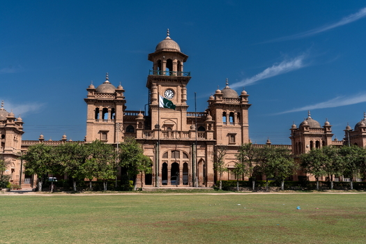 View of the historic Islamia College University Peshawar building with its iconic clock tower red brick facade and green lawn in Peshawar Khyber Pakhtunkhwa Pakistan. View of the historic Islamia College University Peshawar building with its iconic clock tower red brick facade and green lawn in Peshawar Khyber Pakhtunkhwa Pakistan.