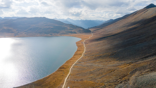 Aerial view of Sheosar Lake surrounded by golden meadows and rugged mountains under a cloudy sky in Deosai Gilgit Pakistan. Aerial view of Sheosar Lake surrounded by golden meadows and rugged mountains under a cloudy sky in Deosai Gilgit Pakistan.