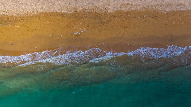 Aerial view of the sandy beach and turquoise sea with white foam waves West Bay England United Kingdom. Aerial view of the sandy beach and turquoise sea with white foam waves West Bay England United Kingdom.