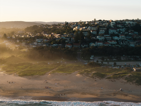Aerial view of Dee Why Beach at golden hour with sand dunes coastal vegetation and residential houses on the hillside in Dee Why New South Wales Australia. Aerial view of Dee Why Beach at golden hour with sand dunes coastal vegetation and residential houses on the hillside in Dee Why New South Wales Australia.