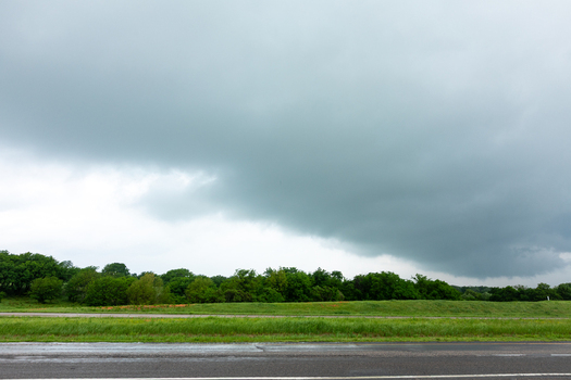 View of a dark ominous storm cloud gathering over a green landscape and a road in Oklahoma City Oklahoma United States.