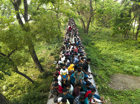 Dhaka Bangladesh 27 March 2026 Aerial view of a dense crowd of people crossing a narrow bridge the vibrant green foliage creating a striking contrast. Dhaka Bangladesh 27 March 2026 Aerial view of a dense crowd of people crossing a narrow bridge the vibrant green foliage creating a striking contrast.