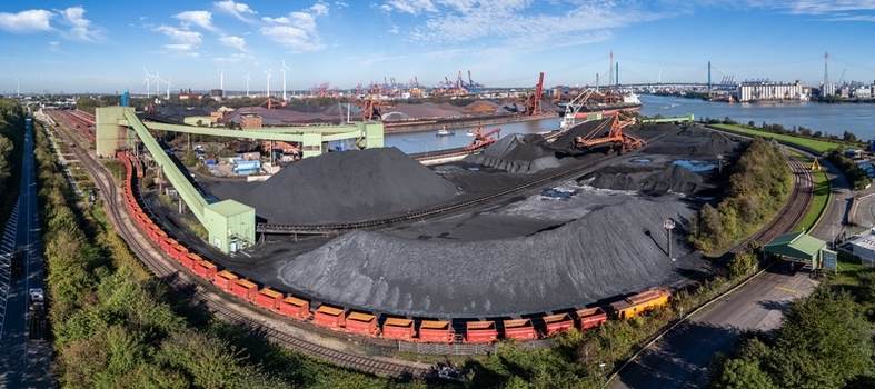 Aerial view of the Am Sandauhafen coal terminal featuring large piles of coal industrial conveyor systems and freight trains along the Elbe river in Hamburg Germany. Aerial view of the Am Sandauhafen coal terminal featuring large piles of coal industrial conveyor systems and freight trains along the Elbe river in Hamburg Germany.