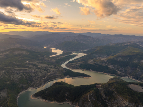 Aerial view of the winding Kardzhali Reservoir surrounded by rugged mountains and lush forests under a vibrant sunset sky in Kardzhali Province Bulgaria. Aerial view of the winding Kardzhali Reservoir surrounded by rugged mountains and lush forests under a vibrant sunset sky in Kardzhali Province Bulgaria.