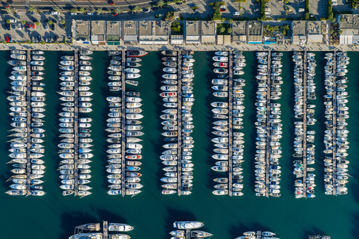 Aerial view of numerous yachts and boats docked in the marina with calm blue water and surrounding harbor infrastructure in Antibes Provence Alpes Cote d Azur France. Aerial view of numerous yachts and boats docked in the marina with calm blue water and surrounding harbor infrastructure in Antibes Provence Alpes Cote d Azur France.