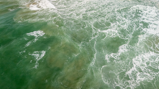Aerial view of turquoise ocean waves crashing with white foam and swirling currents Sagres Faro Portugal. Aerial view of turquoise ocean waves crashing with white foam and swirling currents Sagres Faro Portugal.