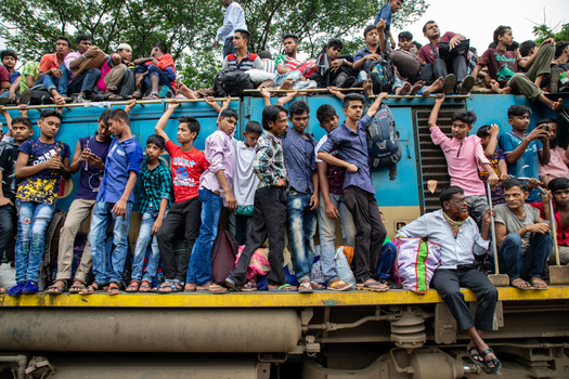 Dhaka Bangladesh 15 June 2018 View of crowds of people hanging onto the side and sitting on the roof of a blue train at Airport Railway Station. Dhaka Bangladesh 15 June 2018 View of crowds of people hanging onto the side and sitting on the roof of a blue train at Airport Railway Station.