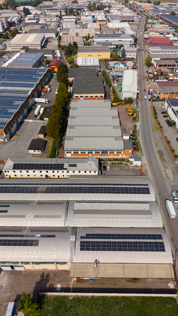 Aerial view of industrial warehouses with solar panels on rooftops paved access roads and commercial infrastructure Milan Lombardy Italy. Aerial view of industrial warehouses with solar panels on rooftops paved access roads and commercial infrastructure Milan Lombardy Italy.