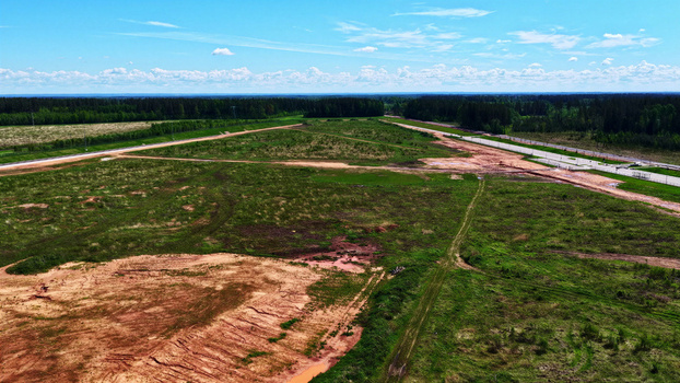 Aerial view of open fields patches of bare earth and a road bordering a dense forest under a bright blue sky in Latvia. Aerial view of open fields patches of bare earth and a road bordering a dense forest under a bright blue sky in Latvia.