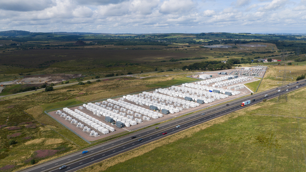 Aerial view of the Coalburn Battery Energy Storage System with rows of white containers and an electrical substation next to a highway in Coalburn Scotland United Kingdom.