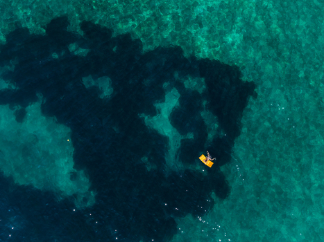 Aerial view of a person floating on a yellow mattress in the crystal clear turquoise waters of Aquarium Beach Jala Vlore County Albania. Aerial view of a person floating on a yellow mattress in the crystal clear turquoise waters of Aquarium Beach Jala Vlore County Albania.